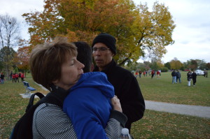 Dale Todd of Cedar Rapids looks on as his son, Adam, hugs his mother, Sara Todd, after the eighth-grader's last cross-country meet of the season. Adam took up running despite having a rare form of epilepsy that causes developmental delays. (photo/Cindy Hadish for Metro Sports Report)