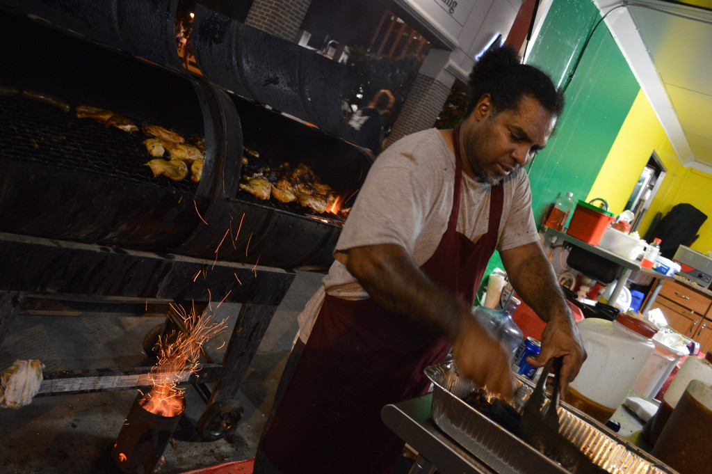 Patrick Rashed of Caribbean Kitchen checks the chicken off the grill at Market After Dark. Rashed said business was excellent at the first nighttime market in Cedar Rapids. (photo/Cindy Hadish)