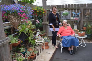 Monica Morley and her mother, Elena Murillo, seated, are shown in the courtyard area of their garden earlier this spring. The succulent plants, to the left, are all wintered over in the basement of their Cedar Rapids home and brought back outdoors for the season. Flowers in the hanging baskets include million bells (Calibrachoa,) lobelia and lantana. (photo/Cindy Hadish)